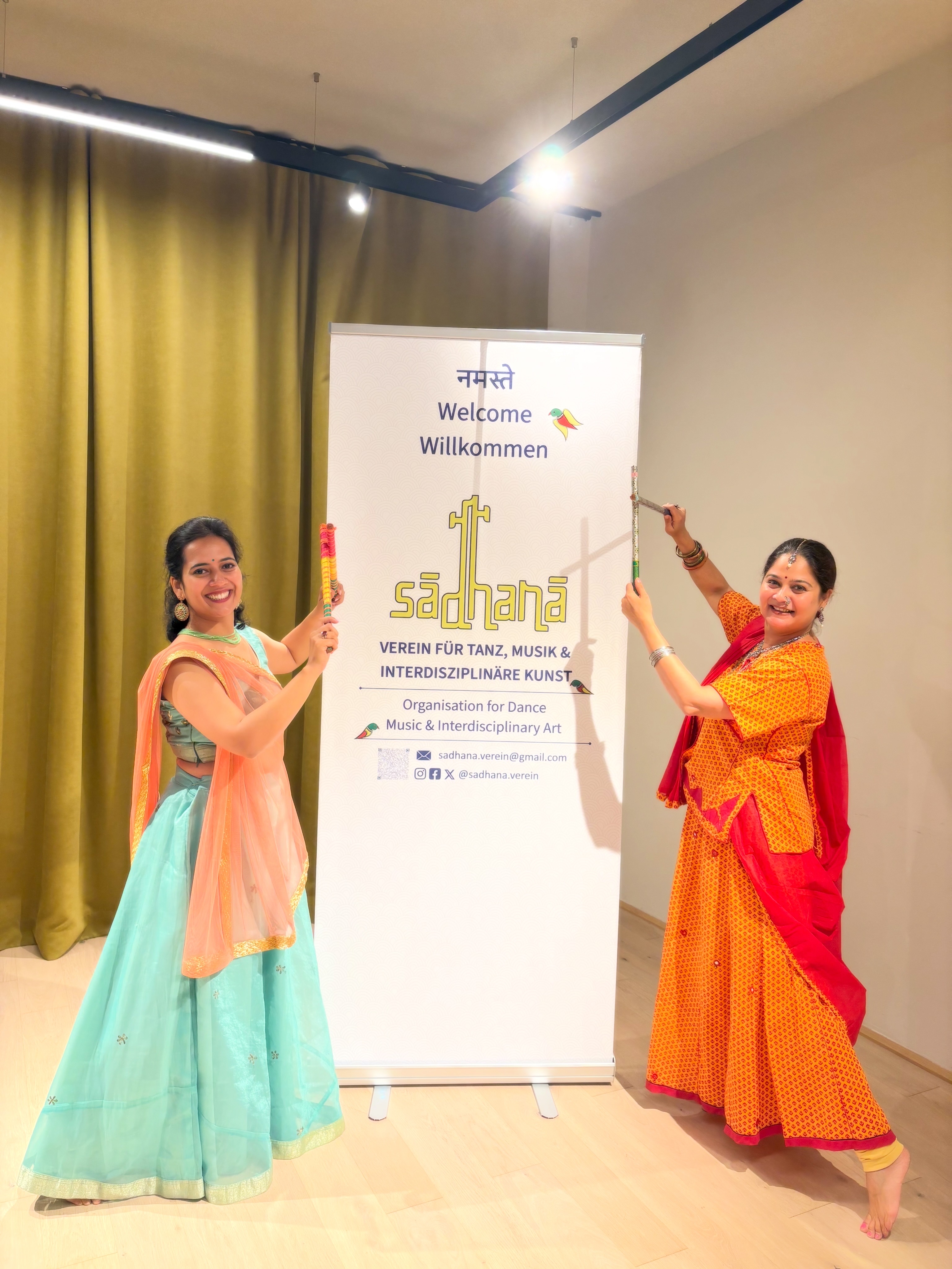 Two workshop participants pose beside the Sadhana Verein welcome banner